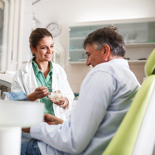 Smiling dentist talking to patient about dental implants