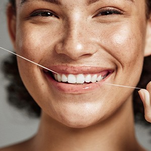 Woman smiling while flossing her teeth