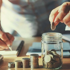 Man dropping a coin into his savings jar