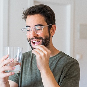 a man with glasses taking a pill